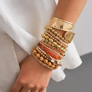 Gros plan d'un ensemble de 12 bracelets bohèmes avec une manchette dorée et perles.