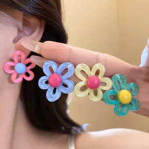 Close-up showing colorful resin flower stud earrings in pink blue yellow and green colors
