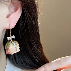 Elegant gold ear hooks with zircon bows and delicate preserved pink rose flower dangles