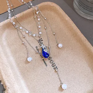 Detailed close-up of a layered pearl necklace featuring a blue teardrop pendant