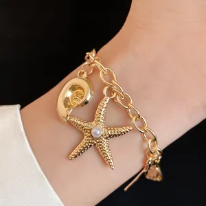 Detailed close-up of a golden holiday style charm bracelet featuring starfish and conch