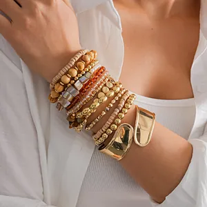 Gros plan d'un ensemble de 12 bracelets avec manchette dorée et perles au poignet.