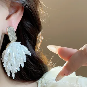 Detailed close-up of elegant white pearl and crystal tassel earrings worn on ear