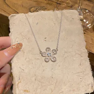 Gros plan détaillé d'un collier en argent avec un pendentif fleur évidée et pierre de zircone