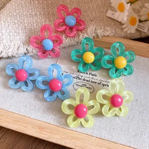 Close-up of colorful resin flower stud earrings on a wooden tray with daisy decor
