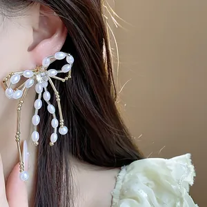 Detailed macro view of elegant bow-shaped pearl earrings featuring a central zircon stone