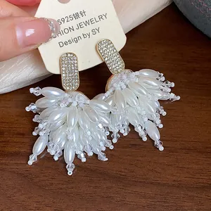 Macro view of luxurious pearl and crystal tassel earrings with gold-toned S925 silver studs.