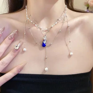 Detailed macro view of a double-layer pearl necklace with a blue water drop pendant