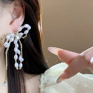 Detailed macro view of an elegant bow earring with white pearls and a central zircon.