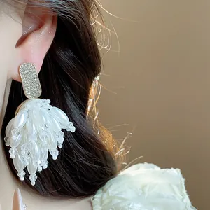 Close-up detail of elegant pearl tassel earrings with sparkling rhinestone studs.