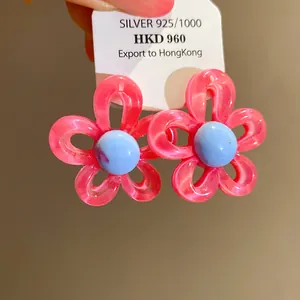 Close-up of pink resin flower stud earrings with blue center on a 925 silver product tag