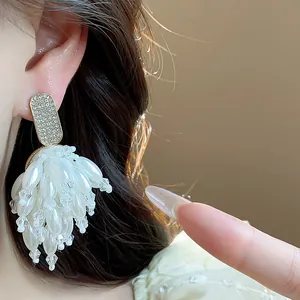 Close-up detail of elegant white pearl tassel earrings with sparkling diamond studs.