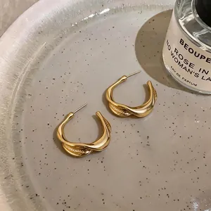 Elegant minimalist gold twisted C-shaped hoop earrings with a pleated texture design