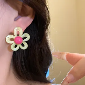 Detailed macro view of a sweet pale yellow resin flower earring with pink center worn on ear