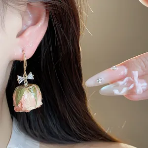 Close-up of a preserved pink rose earring with a zircon-encrusted bow detailing