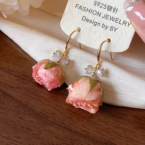 Detailed view of handmade preserved pink rose earrings with a sparkling zircon bow