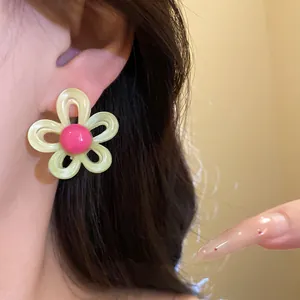 Close-up detail of sweet yellow and pink resin flower stud earrings worn on model's ear