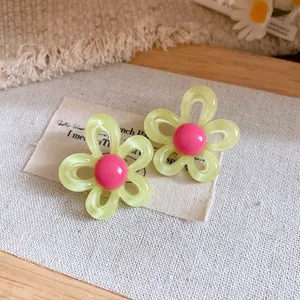 Close-up detail of resin flower stud earrings with pink center and silver needle.