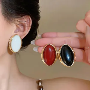 Detail of retro oval resin stud earrings in white, red, and black with gold frame
