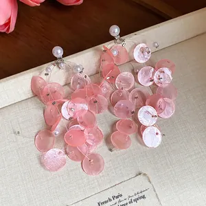 Detalle de pendientes de borla de concha rosa con elegantes perlas blancas.