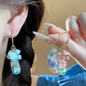Detailed macro view of handmade resin flower earrings with natural stones and gold hooks.