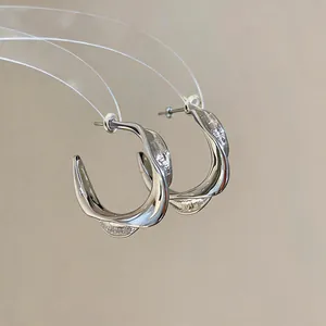 Detailed view of silver-tone twisted C-shape hoop earrings with wrinkled texture