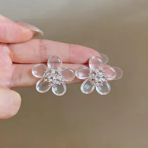 Dettaglio macro di orecchini a lobo trasparenti a forma di fiore con zirconi brillanti