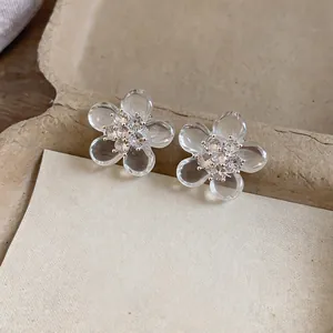 Dettaglio di eleganti orecchini a fiore trasparenti con centri in zircone scintillante.