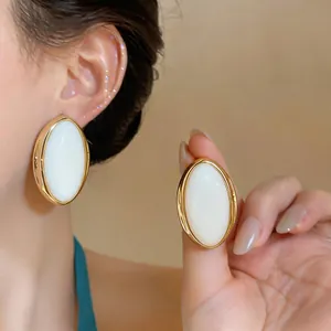 Close-up view of vintage gold-framed oval resin earrings showing elegant wearing effect