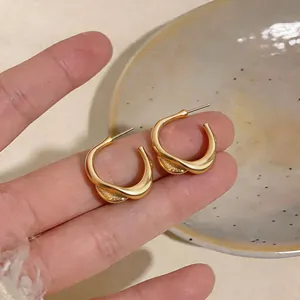 Close-up view of elegant gold twisted C-shaped earrings with minimalist design texture.