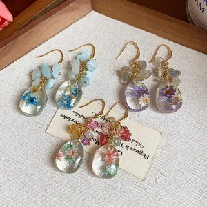 Detail of handmade resin earrings featuring real dried flowers and natural stones
