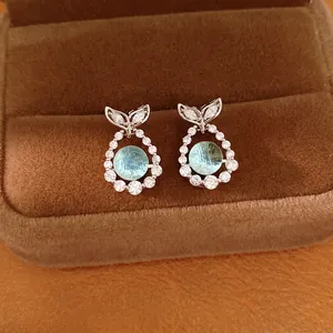 Elegant silver fishtail stud earrings featuring blue zircon and pavé crystals in a box