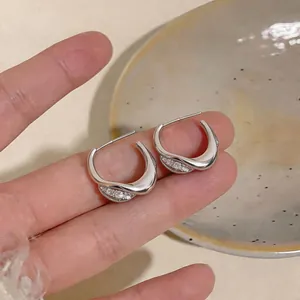 Detailed close-up of silver minimalist twisted C-shaped earrings with sparkling stones