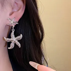 Silver metallic starfish drop earrings with realistic wrinkled texture on Asian model
