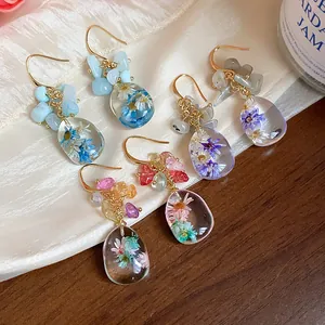 Close-up of handmade resin dried flower earrings with natural stones and gold hooks