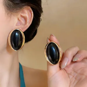 Detail of vintage oval gold-toned stud earrings featuring a smooth black resin center.