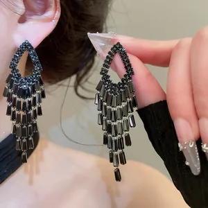 Close-up view of elegant black zircon geometric tassel earrings displayed on a model