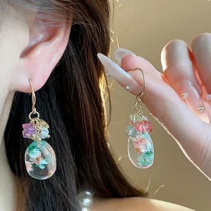 Close-up detail of ethnic style earrings with natural stones and resin flowers.