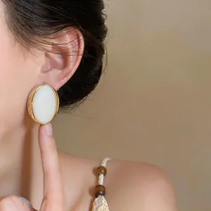 Detailed close-up showing vintage oval resin stud earrings with a gold frame on a model