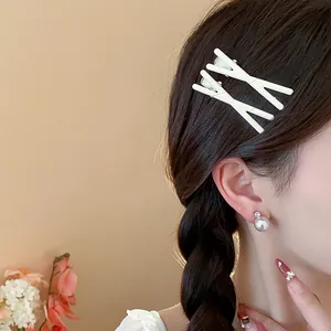 Detailed view of elegant white X-shaped hair clips worn by a model with braided hair.