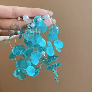 Detalle de los pendientes de borla de concha turquesa con perlas y agujas de plata