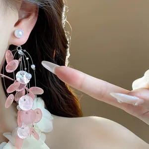 Detalle elegante de pendientes colgantes de concha rosa con perlas en perfil de modelo.