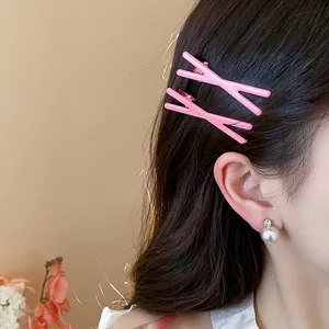 Close-up view of a model wearing two pink X-shaped duckbill hair clips for a stylish look