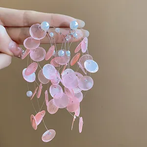 Vista detallada de pendientes de flecos de concha rosa con perlas estilo vacaciones