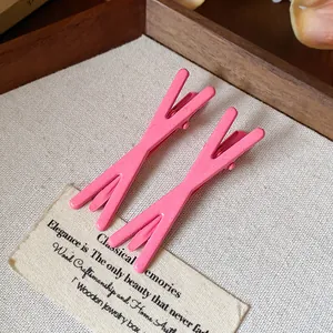 Detail shot of minimalist pink dopamine duckbill hair clips displayed on a wooden tray accessories