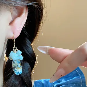 Ethnic style blue natural stone and resin flower drop earrings worn by a model detail
