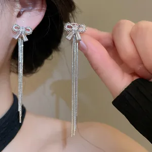 Exquisite close-up of zircon bow-knot stud earrings featuring long silver metal tassels