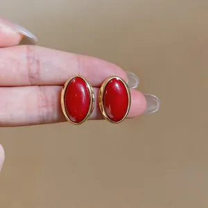 Close-up of vintage oval red resin stud earrings with gold-plated frames