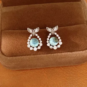 Detail shot of elegant fish tail stud earrings with light blue zircon and silver needles