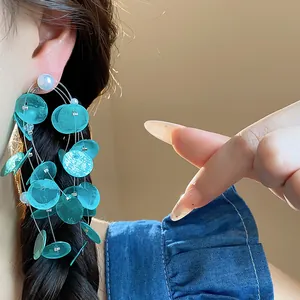 Primer plano de pendientes de borla de concha turquesa con perla lucidos por modelo